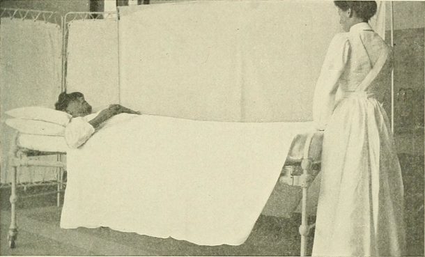 一个女人躺在床上，护士站在旁边
