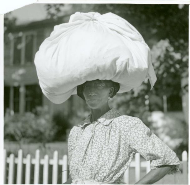 一个女人头上顶着一个用床单包着的大包。