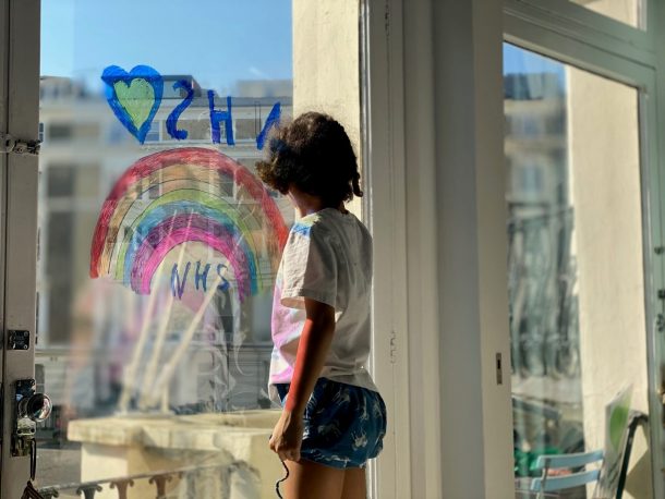 一个孩子看起来窗外,装饰着一道彩虹