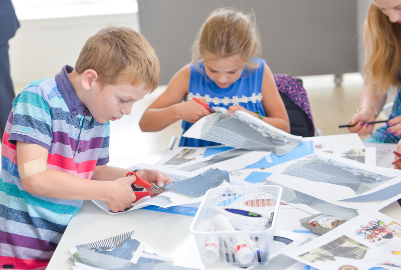 children with paper and scissors crafting at a table.