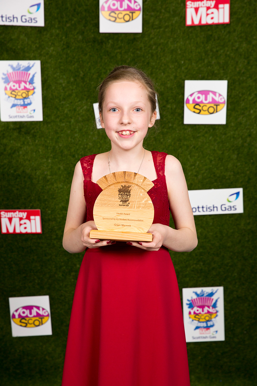 格蕾丝，一个年轻的女孩，穿着一件红色的裙子，拿着她的苏格兰青年奖