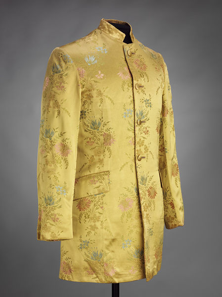 尼赫鲁风格夹克,特点是站衣领和削减。这件夹克是由合成编织提花织物,黄色的地面和花卉图案的蓝色,粉色和绿色。夹克按钮从脖子到腰部有四个self-covered按钮。