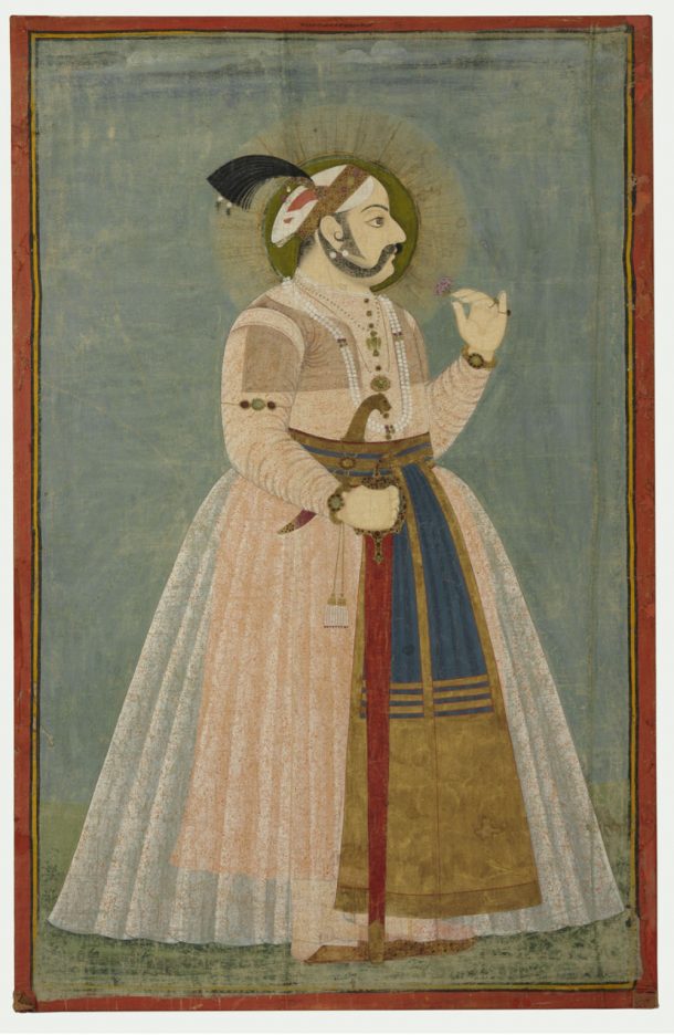 一个男人拿着一朵花，从侧面看向右边。他的右手握着一把插在鞘里的剑。