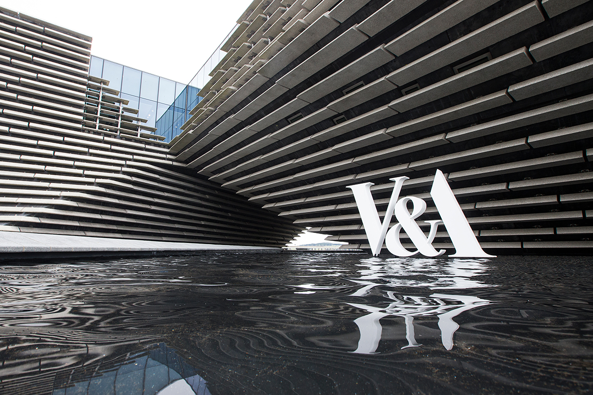 白色的V&A标志在V&A Dundee的灰色石材立面前。